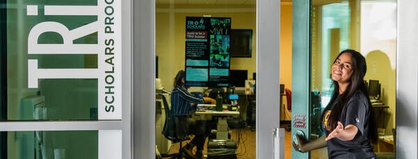 Photo of a student opening the door to the TRIO Scholars office.